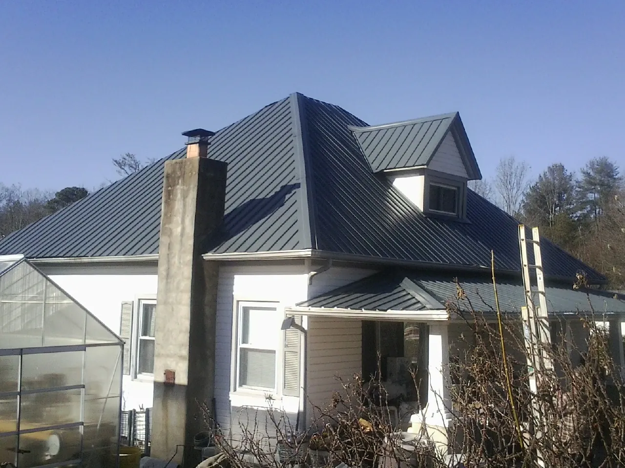 Dark blue standing seam metal roof on a white farmhouse with dormer — Slate & Tile Roof Repair by Roofing Brothers in Murphy