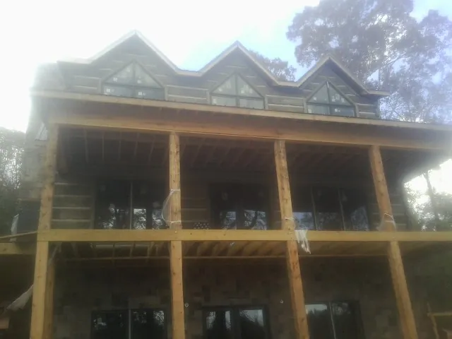 Dormers and porch framing on a large log home under construction — Roof Coating work by our crew in Murphy