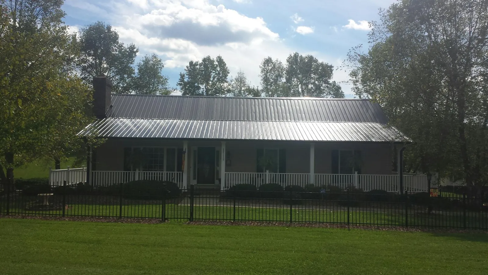 Gray metal roof on a brick ranch with a full width front porch — Gutter Guard Installation work by our crew in Murphy