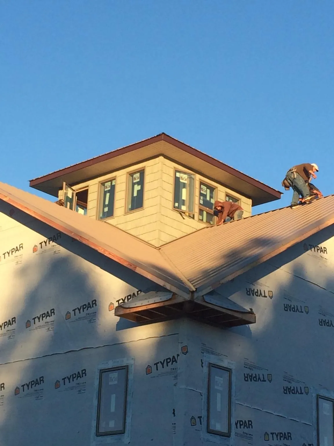 Roofers working around a rooftop cupola on a new metal roof at sunset — Roof Waterproofing in Murphy by Roofing Brothers